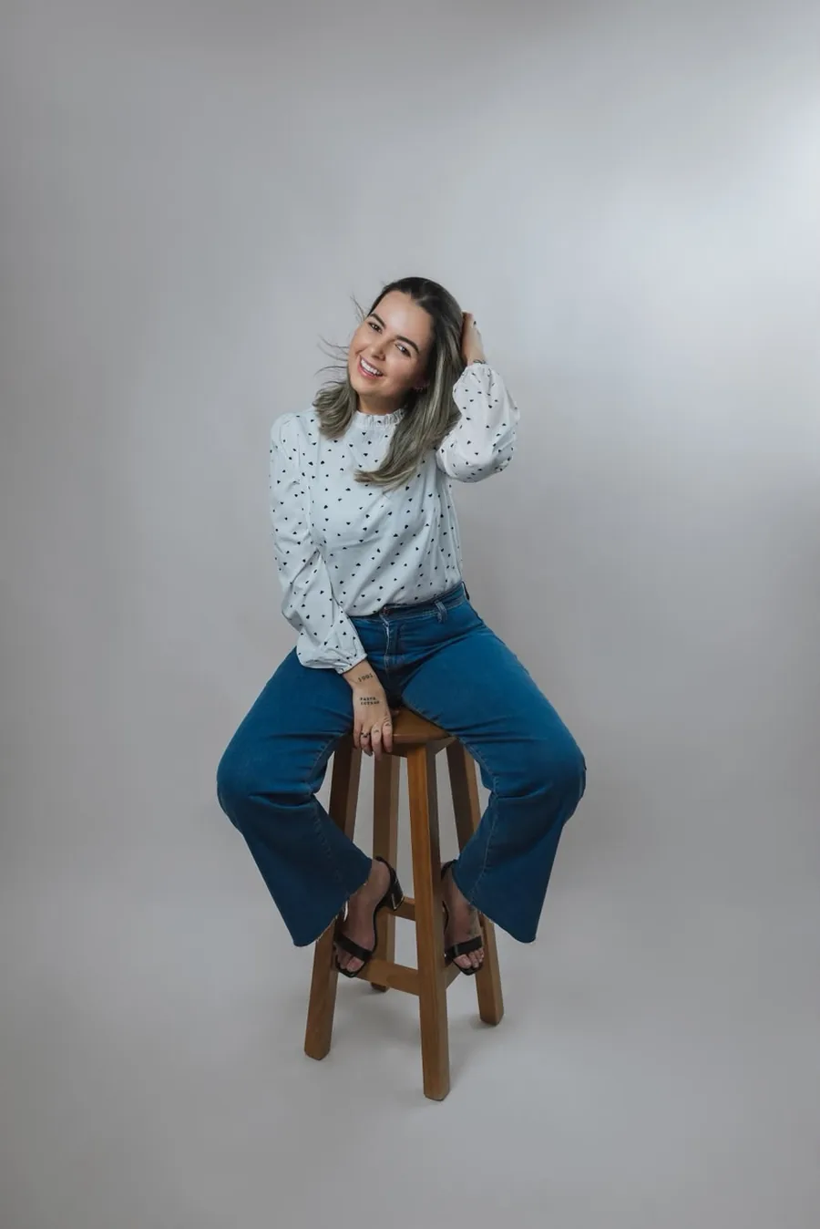 Ana Paula Maia, psicóloga, sentada em um banco alto em foto de estúdio
